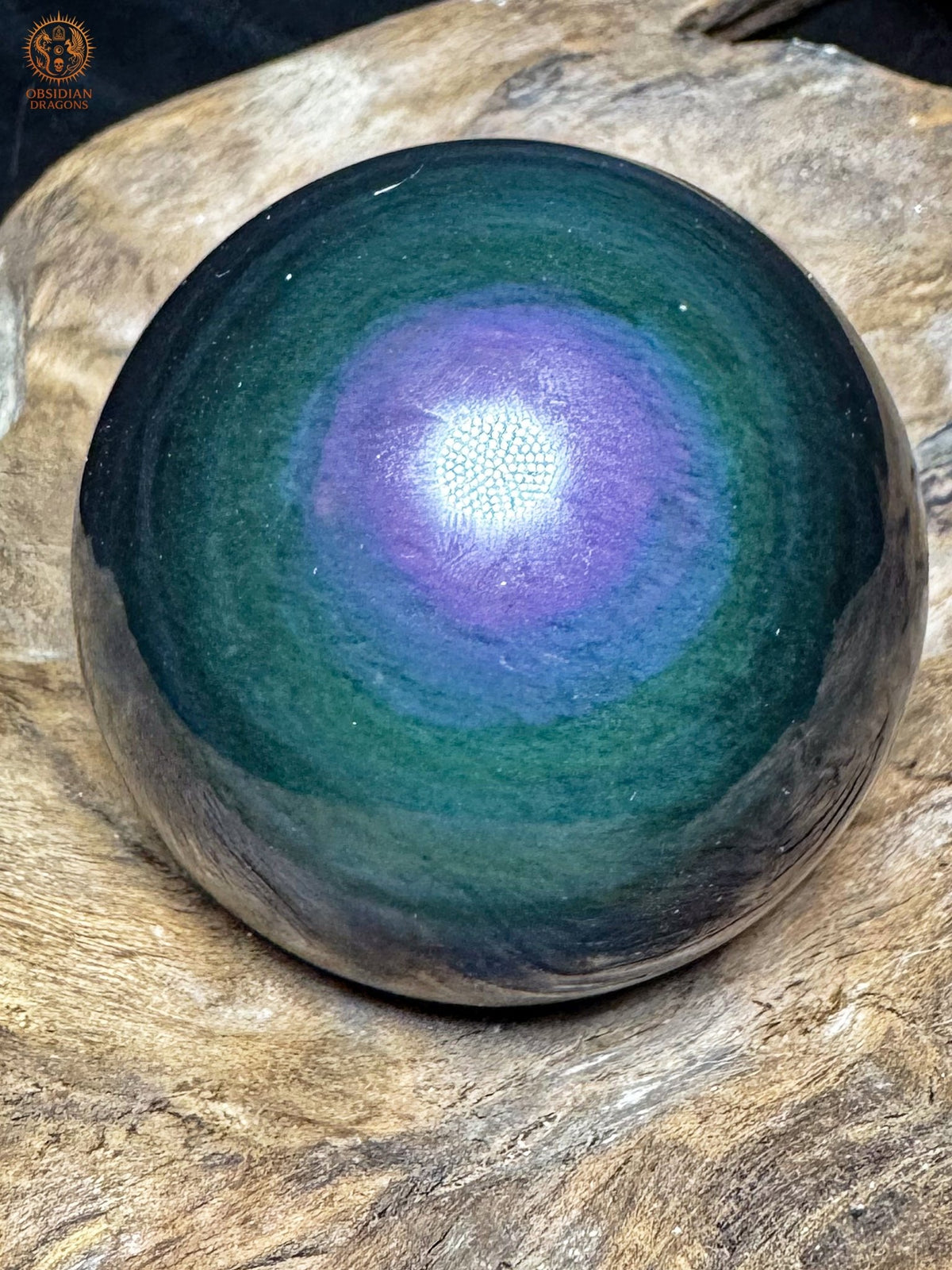 Sphère en obsidienne Manta Huichol du Mexique sur bois, avec une plage violette diffuse entourée de bleu et de vert profond - Obsidian Dragons