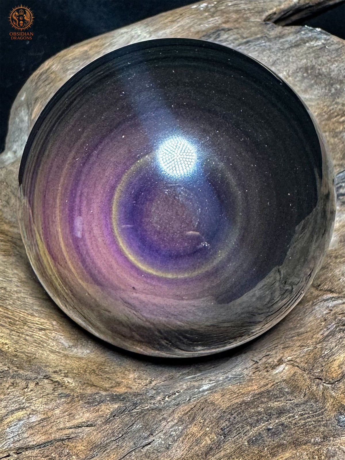 Vue oblique de la sphère en obsidienne œil céleste, avec un œil mauve cerclé de jaune, des bandes violettes et une zone noire à droite