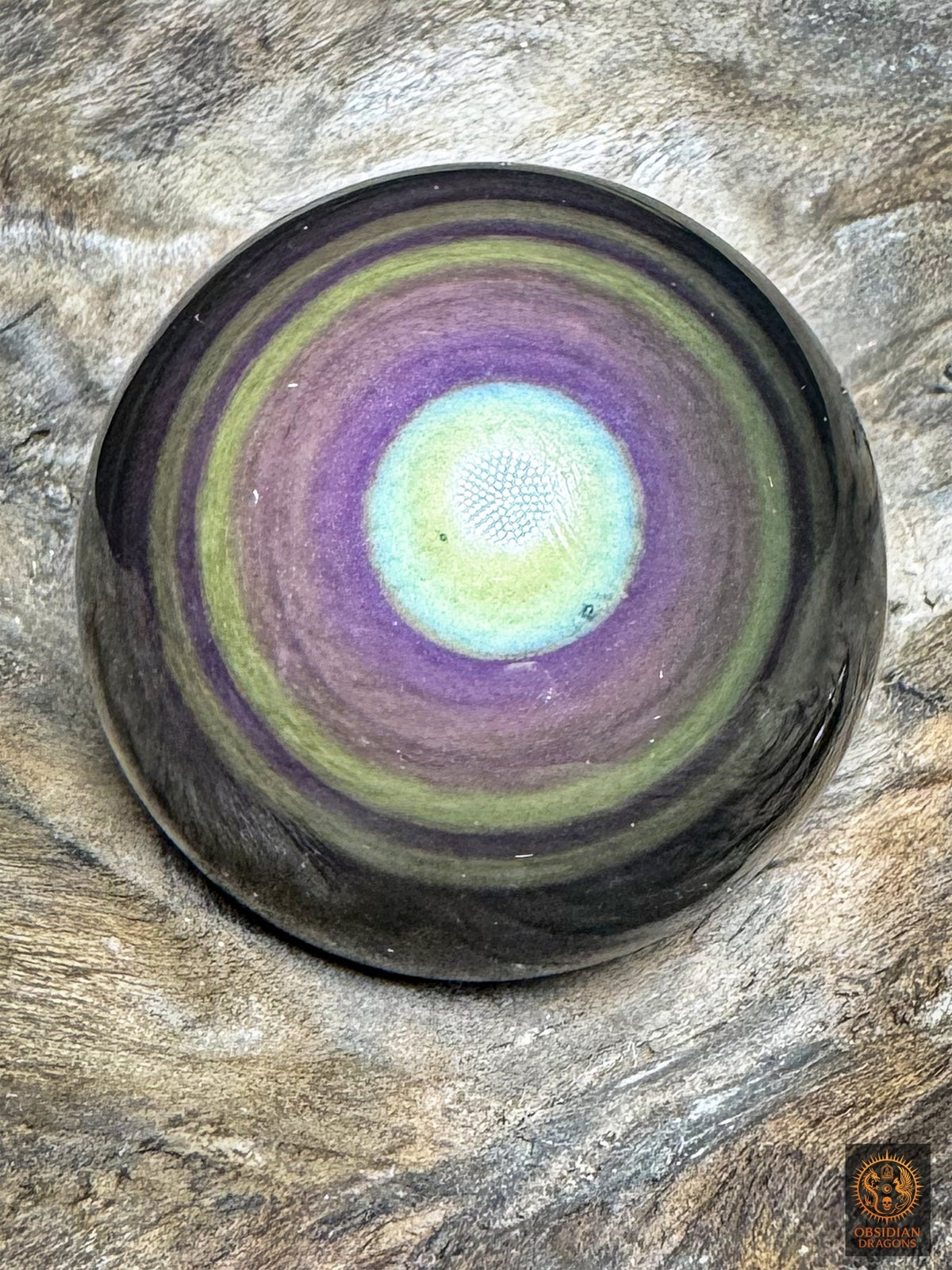 Sphère en obsidienne œil céleste du Mexique de 5,25 cm, cœur jaune-vert bordé de turquoise et couronnes violettes et mauves, sur bois - Obsidian Dragons