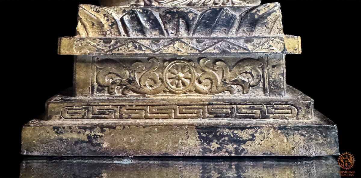 Gros plan sur le socle architectural de la statue d’Acala en bronze, orné d’une roue du Dharma à huit rayons et de motifs géométriques.