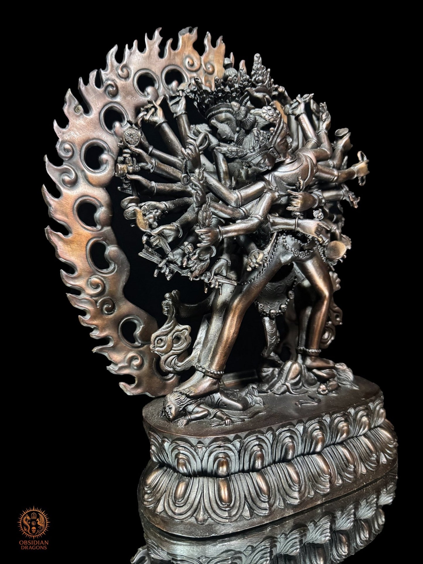 Vue de trois quarts gauche de la statue de Kalachakra en bronze violet révélant la profondeur des bras, attributs et flammes ajourées
