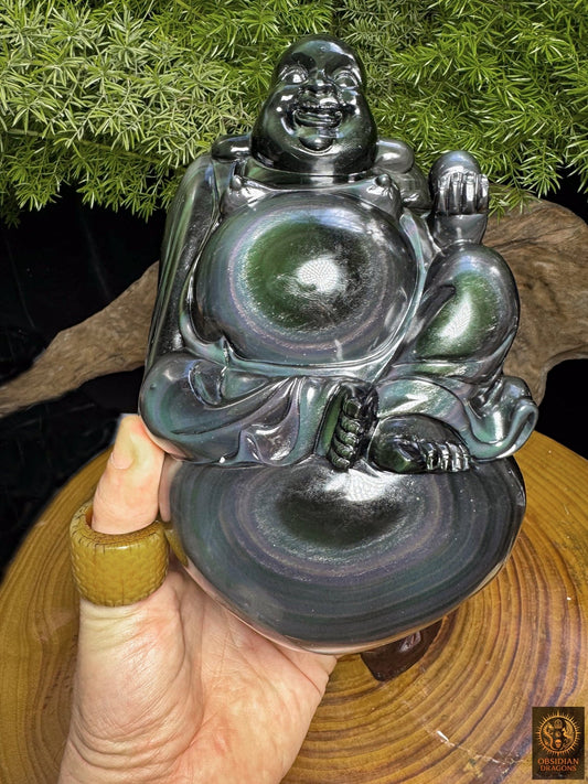 Budai assis sur son sac, sculpté en obsidienne œil céleste et tenu en main, avec des irisations concentriques vertes et violettes - Obsidian Dragons