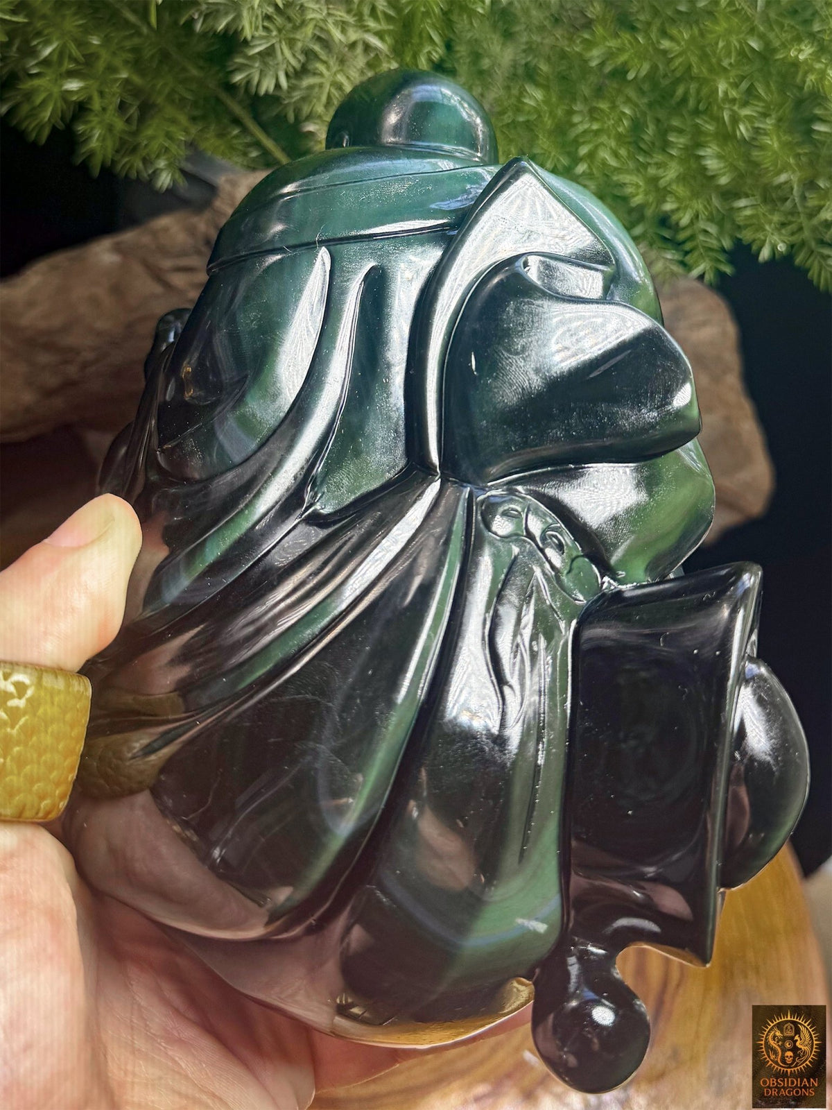Dos de la statuette de Budai en obsidienne œil céleste tenue en main, montrant les plis sculptés du vêtement et les reflets argentés - Obsidian Dragons