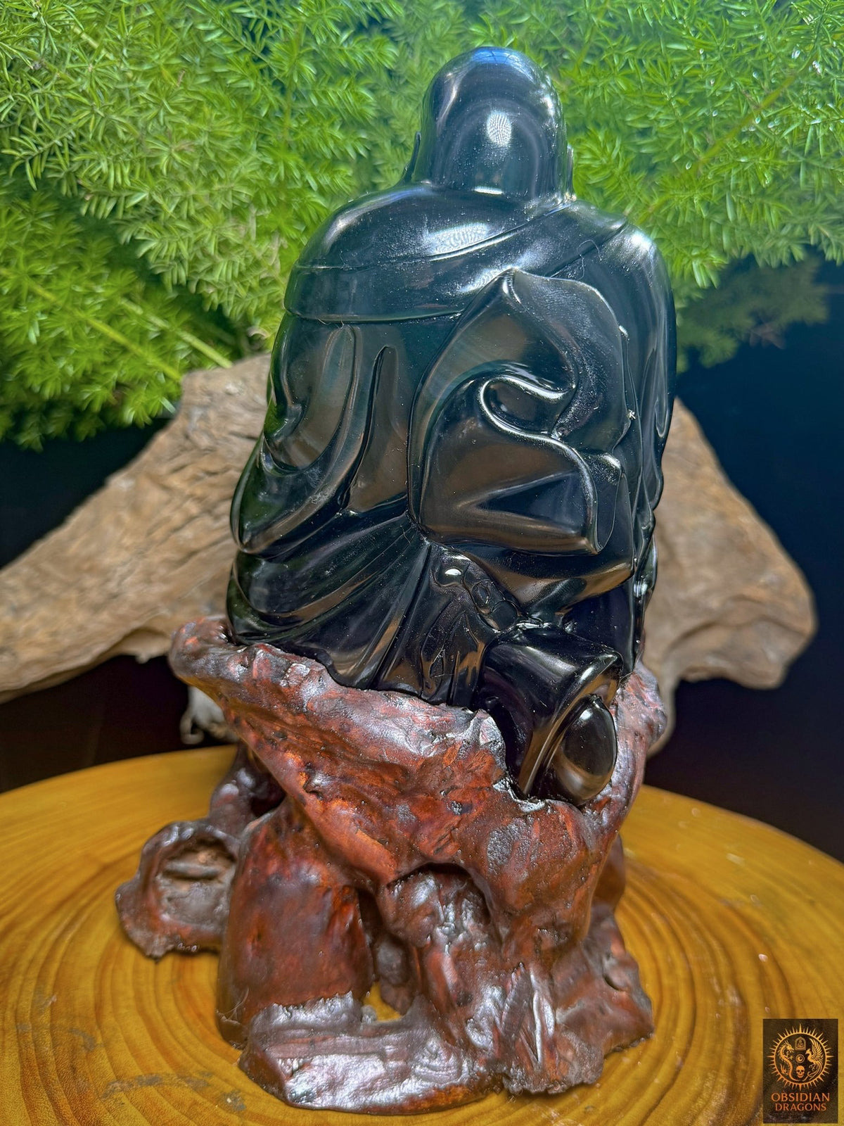 Vue arrière de Budai en obsidienne œil céleste sur socle en cèdre, montrant la tête arrondie et les plis du vêtement dans la pierre polie.