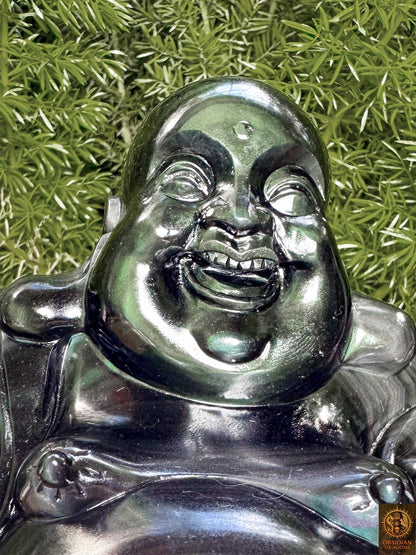 Gros plan du visage souriant de Budai, Bouddha rieur sculpté en obsidienne œil céleste aux reflets verts et argentés.