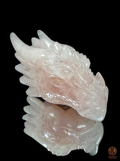 Tête de dragon en quartz rose naturel du Brésil, sculpture artisanale Le Cœur invincible vue de trois quarts avec cornes et écailles
