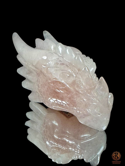 Sculpture de tête de dragon en quartz rose vue de trois quarts, révélant son œil sculpté, ses cornes et les nuances naturelles de la pierre