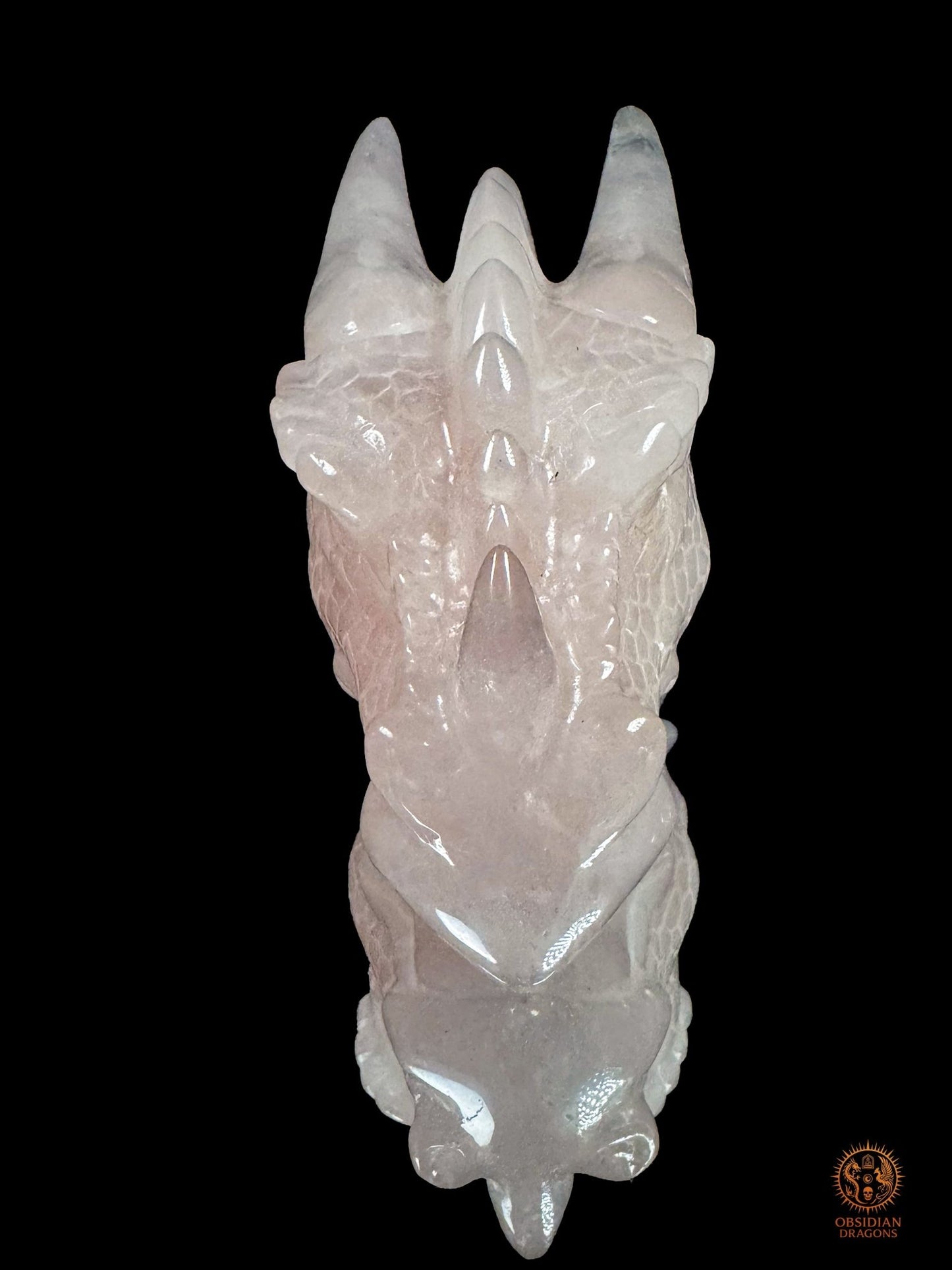 Vue de dessus de la tête de dragon en quartz rose Le Cœur invincible, avec museau allongé, cornes symétriques et crête sculptée