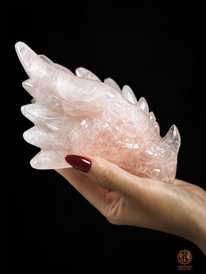 Tête de dragon en quartz rose naturel tenue dans une main pour montrer ses dimensions, sculpture exclusive Le Cœur invincible par Obsidian Dragons